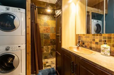 a bathroom with a sink and a washer and dryer at The Qu INN - Cozy Cabin in Parson