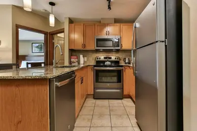 a kitchen with stainless steel appliances and wooden cabinets at Luxury Falcon Crest Lodge 1 Bedroom 1 Pullout Kitchen Hot Tub in Canmore