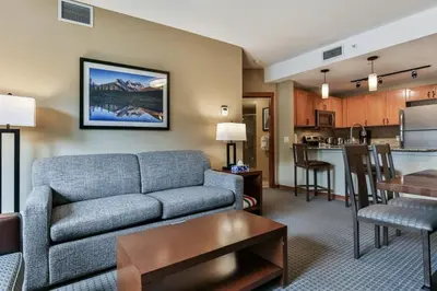 a living room with a couch and a kitchen at Luxury Falcon Crest Lodge 1 Bedroom 1 Pullout Kitchen Hot Tub in Canmore