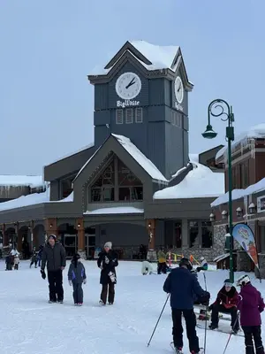 a group of people walking in the snow in front of a building at Magical Views at Southpoint Big White! Best Location! in Big White
