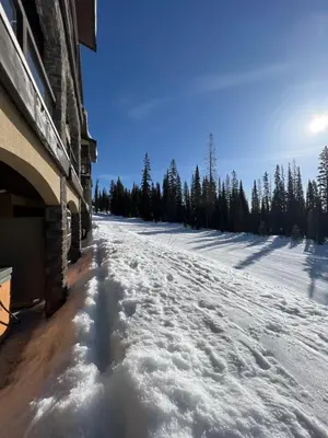 a snow covered road in front of a building at Magical Views at Southpoint Big White! Best Location! in Big White