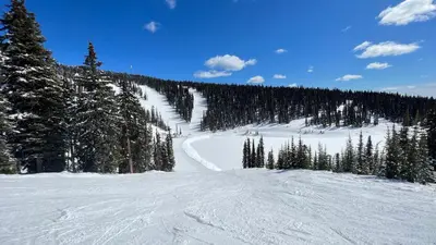 a snow covered slope with trees on a mountain at Magical Views at Southpoint Big White! Best Location! in Big White