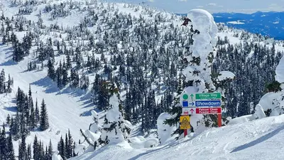 a person on a snowboard on a snow covered mountain at Magical Views at Southpoint Big White! Best Location! in Big White