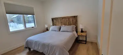a bedroom with a bed with a wooden headboard and a window at Fernie Escape - Mountain Home on the Ski Hill in Fernie