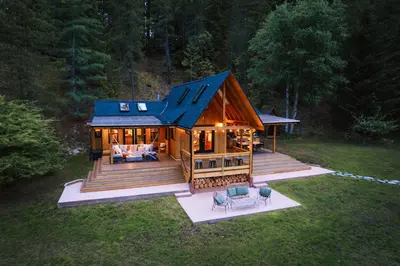 a large wooden cabin with a blue roof at The Kootenay Lake House - A Private Luxury Retreat in Nakusp