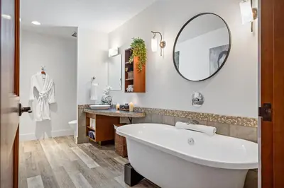 a white bathroom with a tub and a mirror at Luxury Penthouse At Solar A Resort And Spa in Canmore