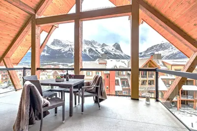 a balcony with a table and chairs and mountains at Luxury Penthouse At Solar A Resort And Spa in Canmore
