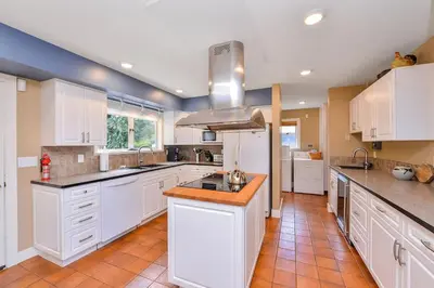 a large kitchen with white cabinets and an island at Kye Bay Winter Beach House by EMR Vacation Rentals in Comox