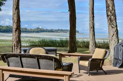 three chairs and tables with a view of the water at Kye Bay Winter Beach House by EMR Vacation Rentals in Comox
