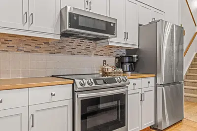 a kitchen with white cabinets and a stainless steel appliance at Attractive Downtown Condo! Hot Tub, Mountain Views managed by Little Sister Getaways in Canmore