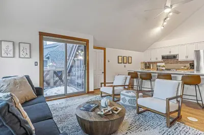 a living room with a couch and a table at Attractive Downtown Condo! Hot Tub, Mountain Views managed by Little Sister Getaways in Canmore
