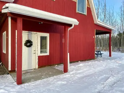 a red barn with a white door in the snow at The Big Red Barn in Whitehorse