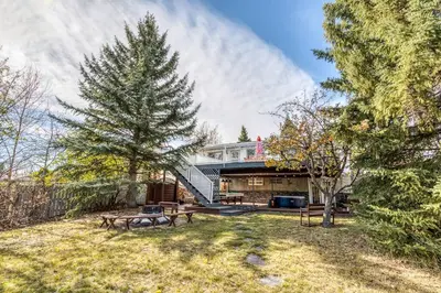 a house with a yard with benches and a tree at Boho Retreat w/King Bed on Bow River Pathway in Calgary
