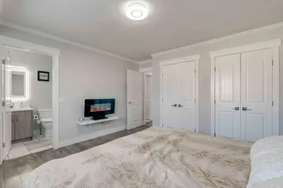 a white bedroom with a bed and a television at Rare Find fully renovated 6 bedroom 3 bath and both levels in Calgary