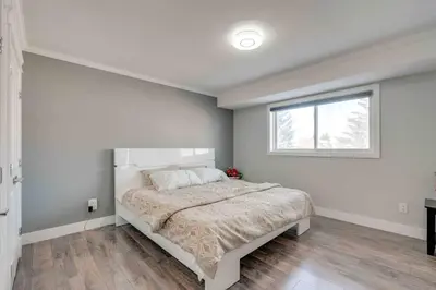 a white bedroom with a large bed with a window at Rare Find fully renovated 6 bedroom 3 bath and both levels in Calgary