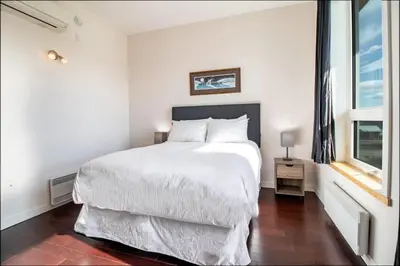 a white bedroom with a large bed and a window at NN - Park View #2 - Downtown 2-bed 2-bath in Whitehorse