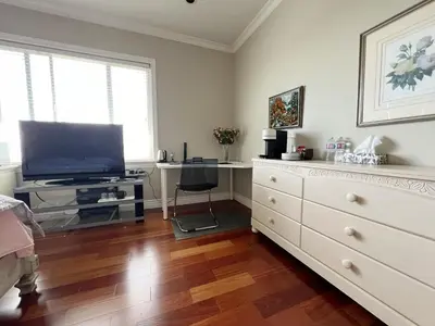 a living room with a television and a dresser at independent entrance cozy room with private bathroom close to YVR Richmond in Richmond