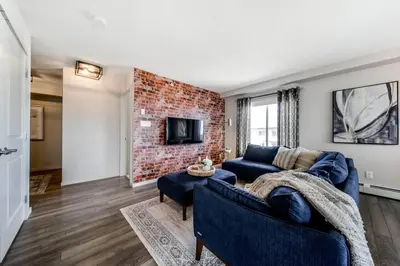 a living room with a blue couch and a brick wall at Bright Luxe Condo, AC, Top Floor, King Bed, Balcony! in Edmonton