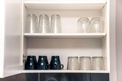 a cabinet filled with glasses and other glass items at Bright Luxe Condo, AC, Top Floor, King Bed, Balcony! in Edmonton
