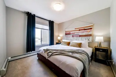 a bedroom with a large bed and a window at Bright Luxe Condo, AC, Top Floor, King Bed, Balcony! in Edmonton