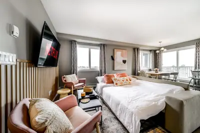 a bedroom with a bed and a tv and chairs at Peaceful Oasis Condo, AC, Top Floor, Secure UG Parking, Balcony, King Bed! in Edmonton