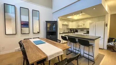 a kitchen with a table and chairs and a refrigerator at 2BR plus Loft, Modern and Spacious, Hot Tub and Sauna, Private Balcony, Fireplace in Whistler