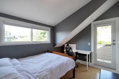 a bedroom with a bed and a desk and two windows at Great West Vancouver house with hot tub, across from beach & 10 mn to Downtown Vancouver in West Vancouver