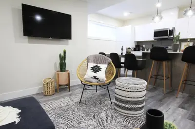 a living room with a chair and a table at Executive Bsmt Suite, King Bed, 5 min to DT & Whyte Ave, Sleeps 6! in Edmonton