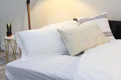 a stack of white pillows on a bed at Executive Bsmt Suite, King Bed, 5 min to DT & Whyte Ave, Sleeps 6! in Edmonton