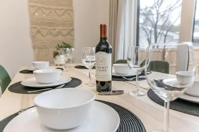 a bottle of wine sitting on a table with glasses at Chic Hideaway, 5BR near DT, Fireplace, King Bed, Fast Wifi, Sleeps 13! in Edmonton