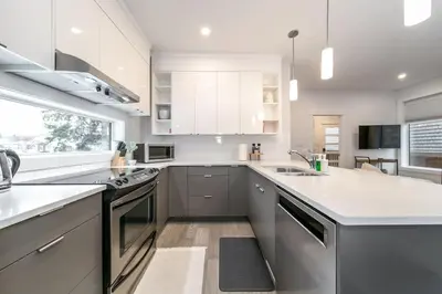 a kitchen with white cabinets and a sink at Chic Hideaway, 5BR near DT, Fireplace, King Bed, Fast Wifi, Sleeps 13! in Edmonton