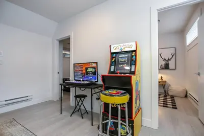 a room with a video game machine next to a desk at Chic Hideaway, 5BR near DT, Fireplace, King Bed, Fast Wifi, Sleeps 13! in Edmonton