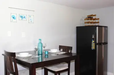 a dining room table with a black refrigerator at 2-Bedroom basement suite with a separate entrance. in Abbotsford