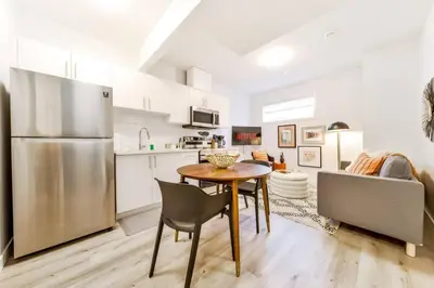 a kitchen with a table and a stainless steel refrigerator at Nordic Retreat, 4BR, Min to WEM & DT, AirCon & Fireplace, Sleeps 10! in Edmonton