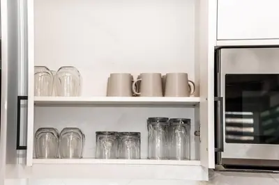 a row of glasses sitting on a shelf next to a microwave at Modern Nordic Escape, 3BR Near WEM & DT, AirCon & Fireplace, Wifi, Sleeps 6! in Edmonton