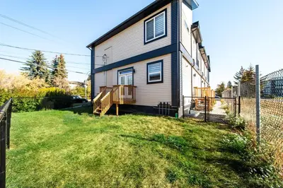 a house with a fence next to a yard at Cozy Nordic Utopia, Bsmt Suite near WEM & DT, King Bed, WiFi in Edmonton