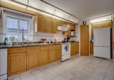 a kitchen with wooden cabinets and a white refrigerator at Big family home w/ Deck, Ping Pong, BBQ & Garage in Edmonton