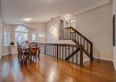 a dining room and living room with a staircase and a table at Big family home w/ Deck, Ping Pong, BBQ & Garage in Edmonton