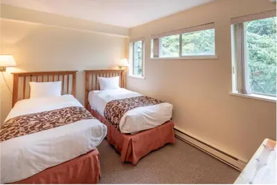 two beds in a room with two windows at Whistler Steps to Village Sleeps 8 + Jacuz + Park in Whistler