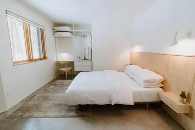 a white bedroom with a bed and a window at Okt Häus in Nordegg