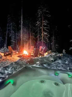 a hot tub in the snow with a fire in the background at Okt Häus in Nordegg