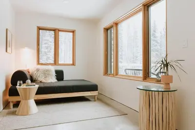 a living room with a black couch and windows at Okt Häus in Nordegg