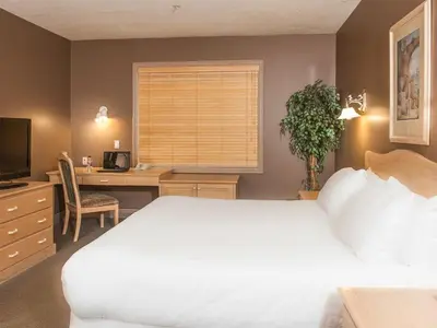 a bedroom with a white bed and a desk and a window at Prime Hotel in Fort McMurray