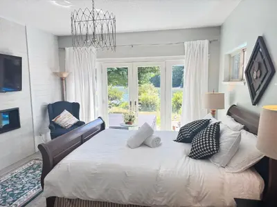 a bedroom with a bed with a chandelier at luxury ocean dock pool villa in Ladysmith