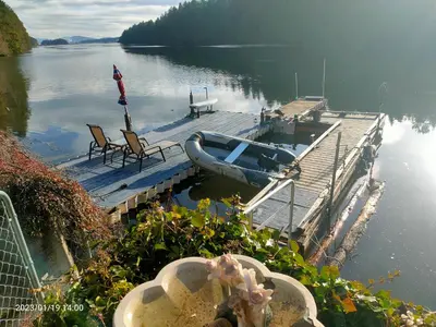 a dock with a boat and chairs on the water at luxury ocean dock pool villa in Ladysmith