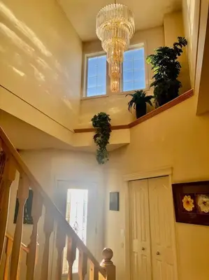 a hallway with a chandelier and a staircase with plants at 2500 sq house in Springbank Hill BL 261818 in Calgary