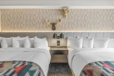 two beds in a hotel room with white sheets at Everwild Canmore Hotel in Canmore