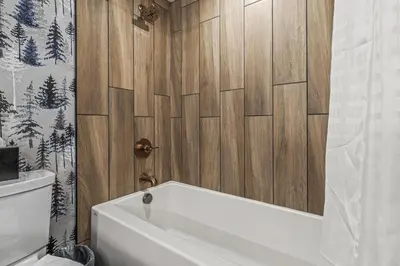 a bathroom with a white tub and a wooden wall at Everwild Canmore Hotel in Canmore