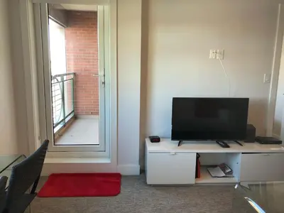 a living room with a television on a table with a window at Amicable, Cozy, High Speed Internet, Sleeps 2 Riverview Downtown Apartment in Calgary