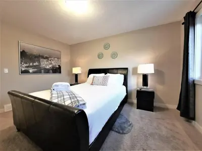 a bedroom with a large bed and a chair at Stylish Getaway by Spruce Meadows in Calgary